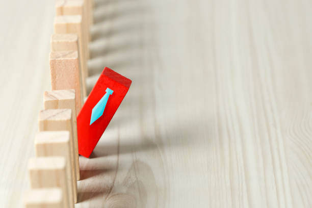 Red block with a tie sticks out of a row a pale wood colored blocks